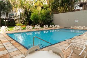 a swimming pool with white chairs and a bunch ofitures at Foz Presidente Economic Hotel in Foz do Iguaçu