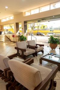 a lobby with chairs and tables in a building at Foz Presidente Economic Hotel in Foz do Iguaçu