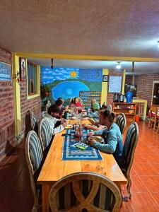 a group of people sitting at a long wooden table at Hostal el Vaquero in Chugchilán