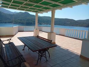 a picnic table and bench on a balcony with a view of the water at Dobrila in Slano