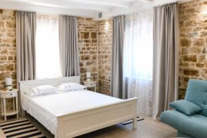 a bedroom with a white bed and a blue chair at Trogir Square Apartment in Trogir