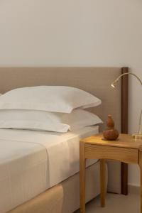 a bed with white pillows and a table with a lamp at Ithaca Garden Villa, Kioni in Kiónion