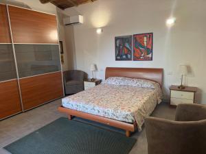 a bedroom with a bed and a cabinet and a chair at S'Abba Druche rooms in Bosa