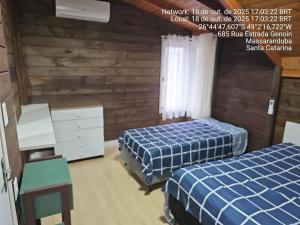 two beds in a room with wooden walls at Recanto Grande Lago in Massaranduba