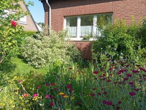 a garden with flowers in front of a house at Wohnung im Grünen in Messenähe in Meerbusch