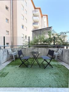 two chairs and a table on the grass in front of a building at Large studio Independent sleeping area Swimming pool in Annemasse
