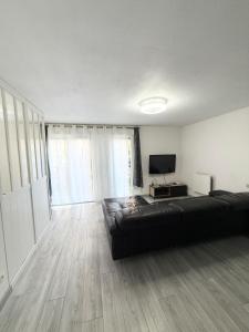 a living room with a black couch and a television at Large studio Independent sleeping area Swimming pool in Annemasse