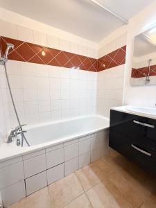 a bathroom with a white tub and a sink at Large studio Independent sleeping area Swimming pool in Annemasse