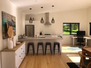a kitchen with a counter and bar stools in it at Ocean Cliff Court in Kuaotunu +14 photos