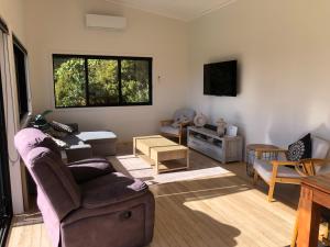 a living room with a couch and a tv at Ocean Cliff Court in Kuaotunu