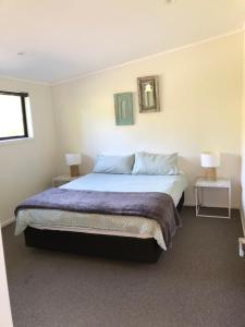 a bedroom with a bed and two tables and two lamps at Ocean Cliff Court in Kuaotunu
