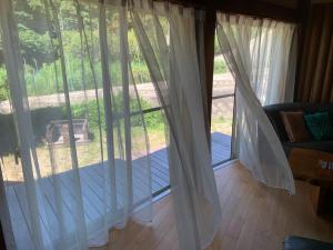 a sliding glass door with white curtains in a living room at ilca イルカの家 -Kumano Kodo Nagaizaka- in Susami