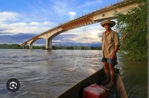 a man in a boat in the water near a bridge at Hostal Mi Puerto in Puerto Triunfo