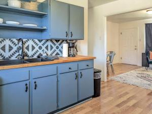 a kitchen with blue cabinets and a wooden floor at Pet-Friendly Downtown Kanab Basecamp | Hot Tub in Kanab +49 photos