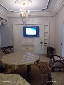 a living room with a table and a tv on the wall at Rez de chaussée in Ifrane