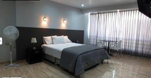 a bedroom with a bed and a table with a fan at Hotel Mochiks Trujillo in Trujillo