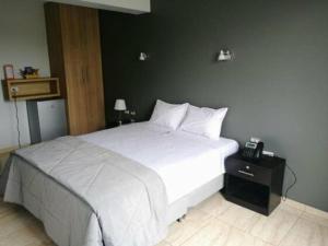 a bedroom with a white bed and a phone on a night stand at Hotel Mochiks Trujillo in Trujillo