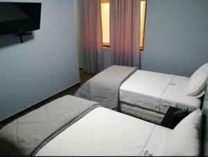 a hotel room with two beds and a flat screen tv at Hotel Mochiks Trujillo in Trujillo