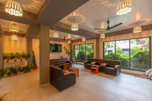 a living room with couches and chairs and windows at Rihiveli Residence Thoddoo in Thoddoo
