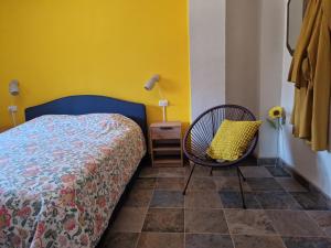 a bedroom with a bed and a chair and a yellow wall at B&B Cortijo Nunca Pense in Órgiva