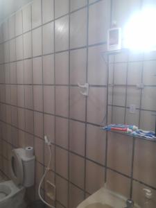 a bathroom with a toilet and a white tiled wall at Casa Marina Morro Branco in Beberibe