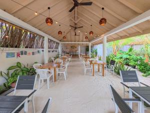 a restaurant with wooden tables and chairs and plants at Rihiveli Residence Thoddoo in Thoddoo