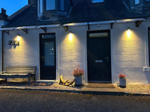 a building with a door and a bench and flowers at Lily Bank Room in Stonehaven