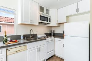 a kitchen with white cabinets and a white refrigerator at Del Mar Studio - Walk to Beach in San Diego