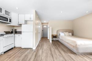 a white bedroom with a bed and a kitchen at Del Mar Studio - Walk to Beach in San Diego