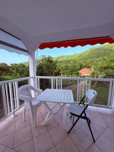 a white table and chairs on a balcony with a view at Studio Arawak in Deshaies