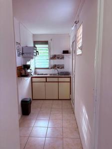a kitchen with white walls and a tile floor at Studio Arawak in Deshaies