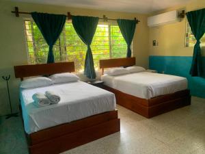 two beds in a bedroom with blue walls and windows at La Morada, una ventana al golfo - Hotel boutique in Monte Gordo
