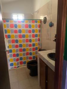 a bathroom with a shower curtain with a toilet and a sink at La Morada, una ventana al golfo - Hotel boutique in Monte Gordo