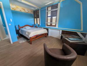 a bedroom with blue walls and a bed and a chair at Villa Ti Balcon avec jacuzzi in Fort-de-France