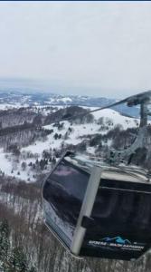 a gondola flying over a snow covered field at Apartman Kopaonik Brzeće in Brzeće +1 photo