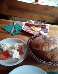 a table with plates of food and a basket of food at Apartman Kopaonik Brzeće in Brzeće