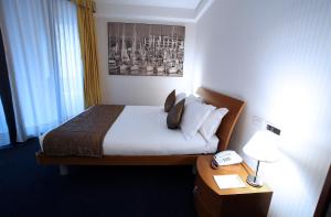 a hotel room with a bed and a table with a phone at Hotel San Rocco in Muggia