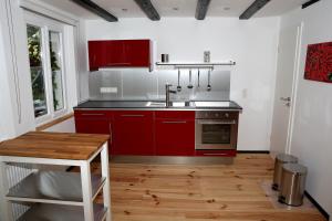 eine Küche mit roten Schränken und einem Waschbecken in der Unterkunft Ferienhaus "Einfach Schön" in Windeck