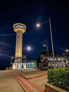 a clock tower at night with the moon behind it at Hostal Mi Puerto in Puerto Triunfo +5 photos
