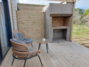 a patio with a fireplace and two chairs and a table at Madera y sal Cabañas piriapolis in Playa Hermosa