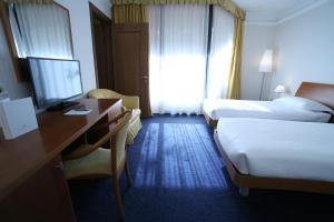 a hotel room with two beds and a desk at Hotel San Rocco in Muggia