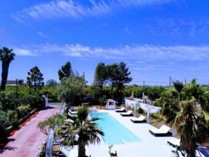a swimming pool with lounge chairs and palm trees at Hotel Residence Noto Marina Relais in Calabernardo