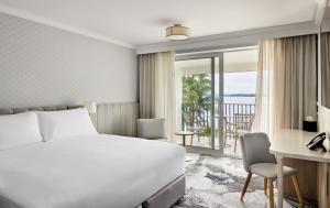 a hotel room with a bed and a desk and a view at The Beachcomber Hotel & Resort in Toukley
