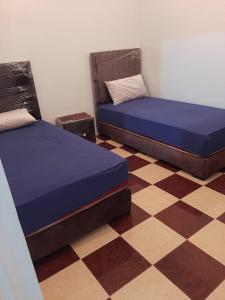 a bedroom with two beds and a checkered floor at agadir location vacance aourir plage in Aourir