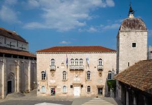 a large brick building with a clock tower at Trogir Square Apartment in Trogir