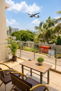 an airplane flying over a balcony with a table and chairs at Sai Grand Villas & Hotel Near Bengaluru Airport in Bangalore +30 photos