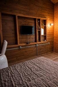 a bedroom with a television in a wooden wall at Chalé Recanto da Cuesta in Botucatu