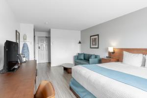a bedroom with a bed and a couch and a television at Ramada by Wyndham Surrey/Langley in Langley