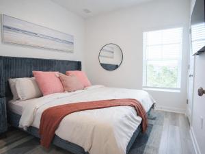 a white bedroom with a large bed with pink pillows at The Palm LK Private Beach Club 100"TV in Pensacola +37 photos