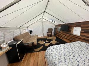 a room with a tent with a bed and a couch at GlampCamp in Big Arm
